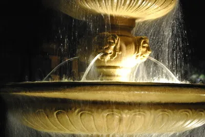 Illuminated stone fountain with streams of water at night
